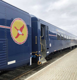 Timmins Care A blue train carriage with a yellow and red emblem on the side, parked at a Timmins station platform. Cochrane District Social Services Administration Board