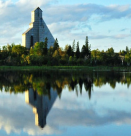 Timmins Care A church in Timmins reflected in the still waters of a lake amidst trees under a partly cloudy sky. Cochrane District Social Services Administration Board