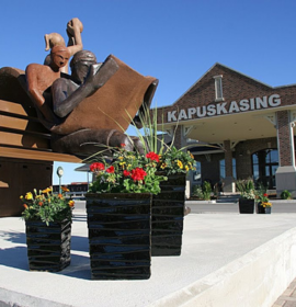 Timmins Care A statue of a figure reading a book in front of the Cochrane District Social Services Administration Board office, adorned with flower planters. Cochrane District Social Services Administration Board